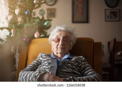 Sad Old Woman Sitting Alone On Sofa.