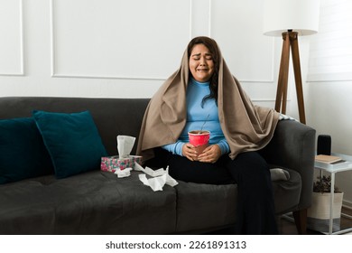 Sad overweight woman crying wrapped in a blanket while eating chocolate ice cream because of her sad breakup