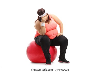 Sad overweight woman sitting on an exercise ball isolated on white background