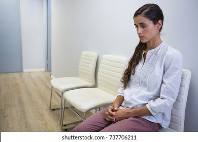 Sad patient sitting on chair in waiting room at hospital - Powered by Shutterstock