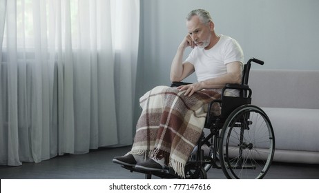 Sad Pensioner Sitting In Wheelchair And Waiting For His Family At Nursing Home