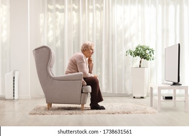 Sad And Pensive Elderly Woman Sitting Alone In An Armchair At Home