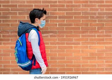 Sad And Pensive Kid With Protective Surgical Mask And Backpack Going To School Outdoor