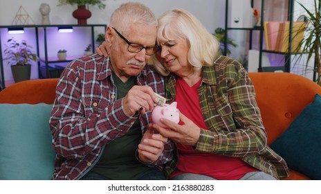 Sad Poor Old Senior Family Grandparents Man Woman Counting Money From Piggybank At Home. Mature Grandmother Grandfather Holding Last One Dollar Cash. Poverty Debt Financial Problem, Pension Retirement