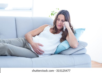 Sad Pregnant Woman Lying On Sofa At Home