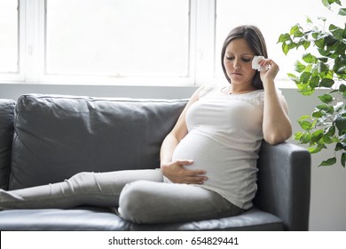 A Sad pregnant woman lying on sofa at home - Powered by Shutterstock