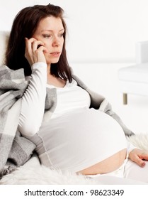 Sad Pregnant Woman Talking Mobile Phone At Home