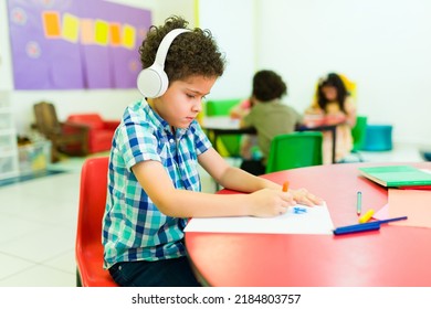 Sad preschool student boy with autism wearing headphones and feeling isolated from his classmates in kindergarten  - Powered by Shutterstock