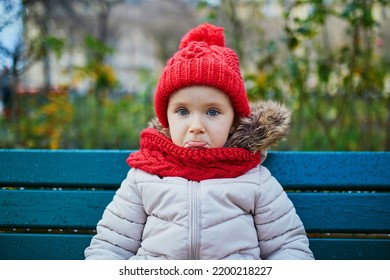 Sad Preschooler Girl Sitting On The Bench On A Street Of Paris, France