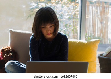 trauriges Quarantäneschluss-Kind, das vom Heimcomputer und den Online-Klassen lernt, während traurige covid-19-Pandemie-Sperrung, grüner Balkon-Hintergrund