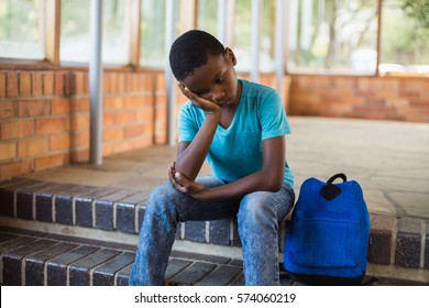 Sad Schoolboy Sitting Alone On Staircase At School