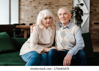 Sad Senior Couple Hugging On Sofa During Self Isolation