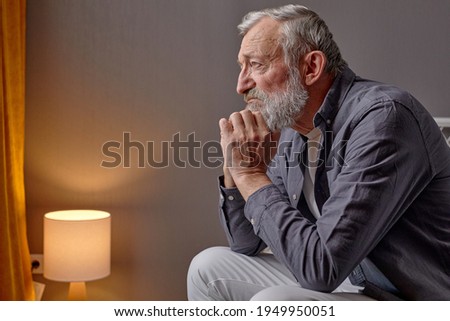 Sad senior man looking down with anxiety, thinking about something sad