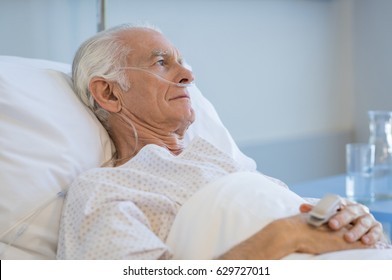 Sad Senior Man Lying On Hospital Bed And Looking Away. Old Patient With Oxygen Tube Feeling Lonely And Thinking At Hospital. Sick Aged Man Lying Hospitalized In A Medical Clinic.