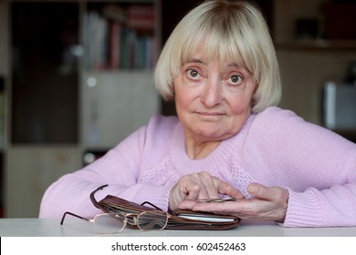 Sad Senior Woman, An Elderly Pensioner Counting Coins On Her Palm, Wallet With Money, Eye-glasses At The Table, Concept Of Financial Security In Old Age, Indoor Portrait, Focus On The Hand With Coins