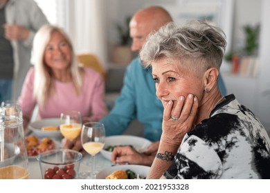 Sad Senior Woman With Friends Having Party Indoors, Eating At The Table.