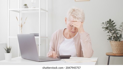 Sad Senior Woman Sitting At Table With Laptop, Feeling Pressure Because Of Payment Problem, Feeling Anxious Over Money 