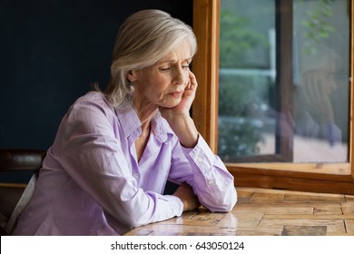 Sad Senior Woman Sitting At Table In Cafe Shop