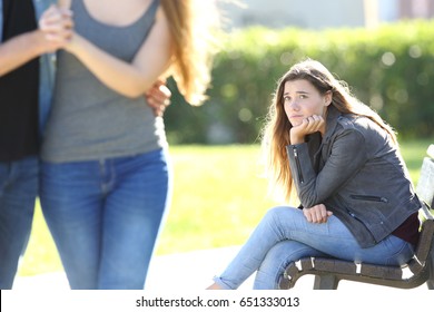 Sad Single Girl Seeing An Affectionate Couple Who Are Walking Outdoors In A Park