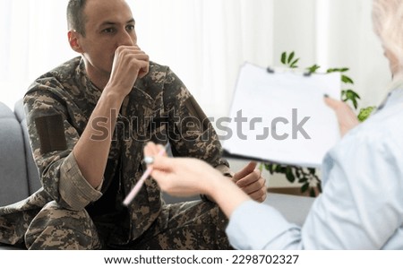 sad soldier with ptsd talking at psychiatrist and gesturing while sitting on couch during therapy session