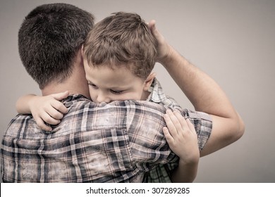 Sad Son Hugging His Dad Near Wall At The Day Time