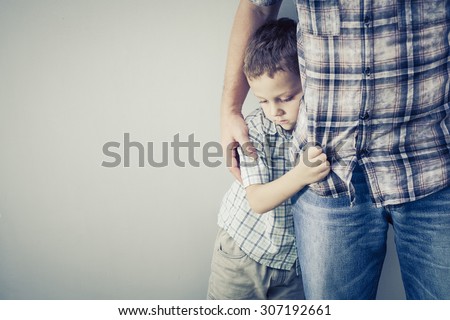 sad son hugging his dad near wall at the day time