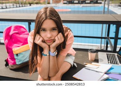 Sad sorrowful high school girl teenager pupil college student in casual clothes with bag using laptop doing home work task sitting alone in sport yard basketball court copy space. Education concept - Powered by Shutterstock