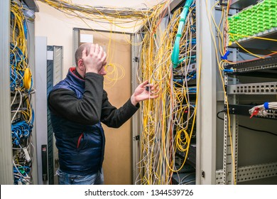 A Sad Specialist Took Up His Head At The Sight Of Problems With Wiring In The Server Room. Facepalm Technician. Incorrect Connection Of Communication Equipment In The Data Center.