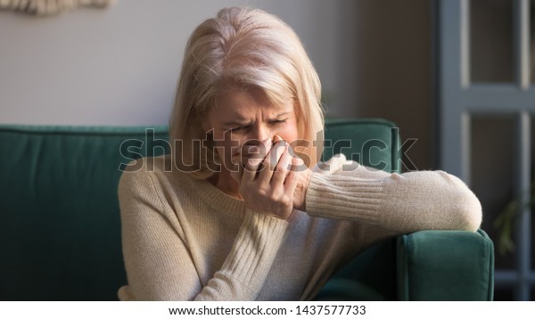 Sad stressed old middle aged woman widow mourning\
crying alone sit on couch at home, upset desperate senior mature\
elder grandma grieving weeping suffering from anxiety grief sorrow\
disease concept
