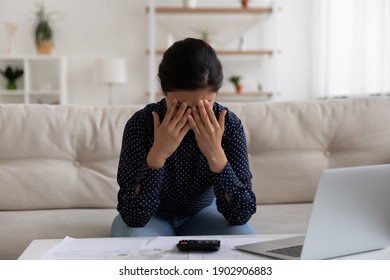 Sad stressed young indian female deal with bankruptcy of her small business having huge loan mortgage debt. Upset depressed mixed race woman crying at home office after losing money in fraudulent deal