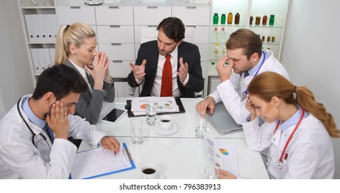 Sad Team of Medical Doctors Receive Bad News from Hospital Manager Man at Monthly Meeting in Board Room, Medicine People Looking on Pie Chart Profit Data