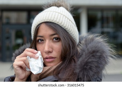 Sad Tearful Woman In Warm Winter Fashion Holding A Handkerchief To Her Face To Dry The Tears From Her Eyes Looking Into The Camera