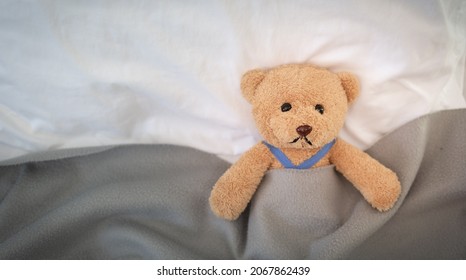 A sad teddy bear lies sick in bed with disappointment and discouragement