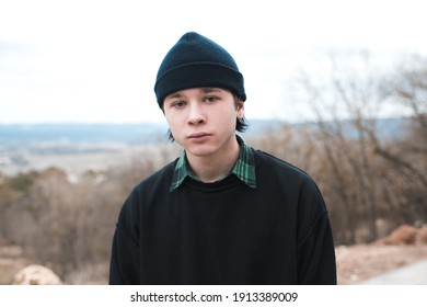 Sad teen boy 18-19 year old wearing knitted hat and sweatshirt posing outdoors closeup. Looking at camera. 20s. Teenagerhood. 