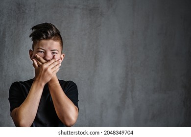 Sad teen boy covered his mouth with his hands. Problems of suppression of emotional detachment and isolation of adolescent children. Difficulties growing up during the transition period - Shutterstock ID 2048349704