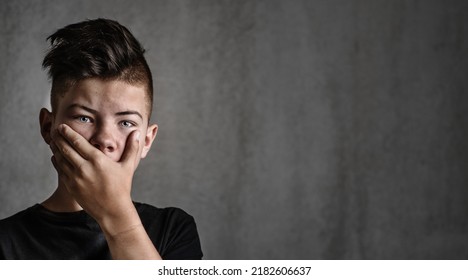 Sad Teen Boy Covered His Mouth With His Hands. Problems Of Suppression Of Emotional Detachment And Isolation Of Adolescent Children. Difficulties Growing Up During The Transition Period