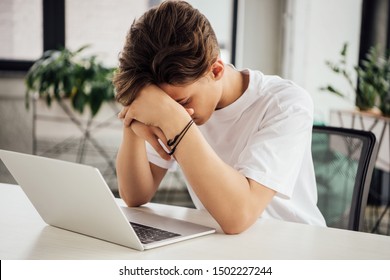 Sad Teen Boy In White T-shirt Using Laptop At Home