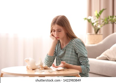 Sad Teen Girl With Broken Piggy Bank And Money At Home