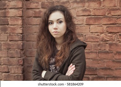 Sad Teen Girl. Introvert Girl With Long Brown Hair Near The Brick Wall. Troubled Teen On The Street