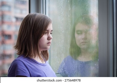 Sad Teen Girl Looking Into Rain Window