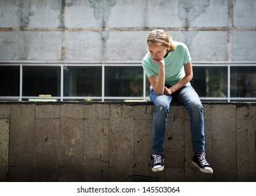 Sad teen girl sitting on a concrete parapet. Real people series - Powered by Shutterstock