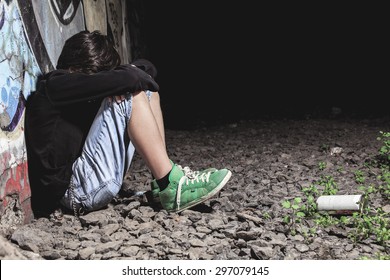 A Sad Teen Sit On The Ground Of A Graffiti Wall