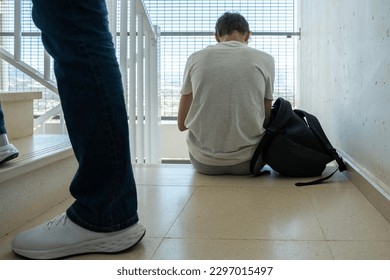 Sad teenage boy with mobile phone and backpack sitting on stairs. Teenager surfing on Internet, watching video, using app. Education, learning difficulties, mobile addiction concept - Powered by Shutterstock