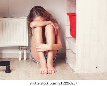 Sad Teenage Girl Is Sitting Upset Under The Table In Her Room. A Child Suffers Because Of Bullying At School Or Domestic Violence