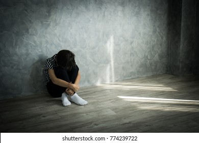 Sad teenager boy sitting alone lonely on the floor leaning against the wall - Shutterstock ID 774239722