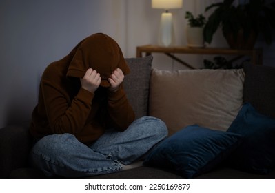 sad teenager girl sitting on couch indoor at night - Shutterstock ID 2250169879