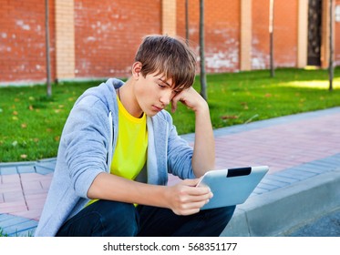 Sad Teenager With Tablet Computer On The Street