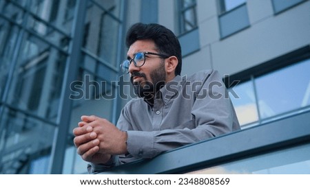 Sad thoughtful man Indian Arabian pensive businessman entrepreneur employer on terrace balcony outdoors depressed upset male worker in city concerned with business failure difficult decision crisis