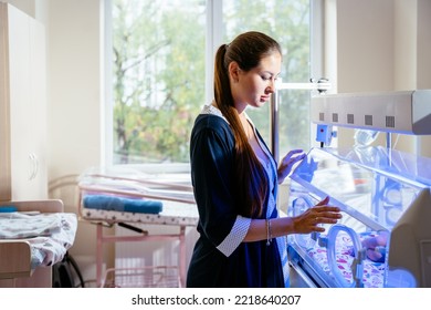 Sad Thoughtful Mother Looking At Her Newborn Baby In An Incubator In Hospital. Phototherapy Treatment To Reduce Bilirubin Levels In Newborn Jaundice.