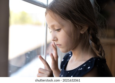 Sad Thoughtful Orphan Child Got Trauma, Feeling Depressed, Lonely, Upset. Serious Bored Girl Standing By Window, Thinking, Touching Glass. Childhood Problems, Abuse, Violence In Family Concept